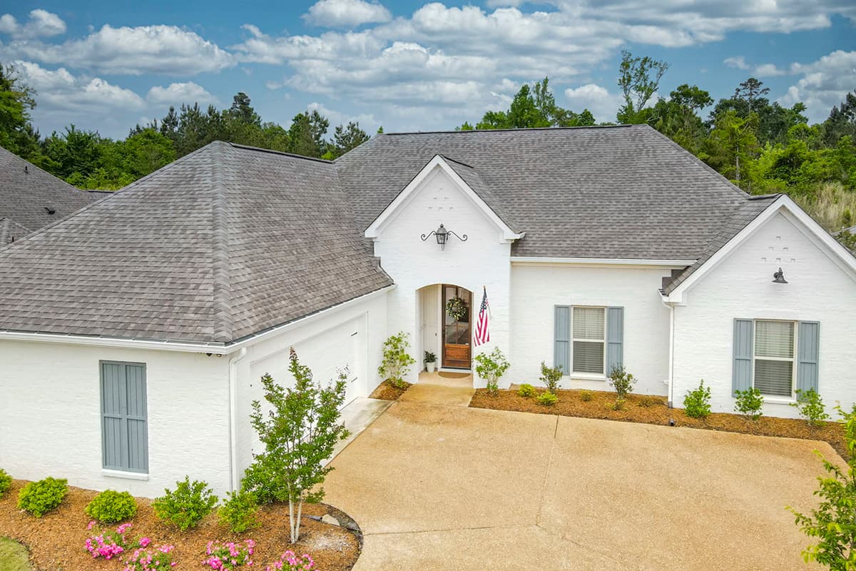 House plan exterior: Ranch style, white brick, attached garage, arched entry with decorative lantern, and gabled dormers.