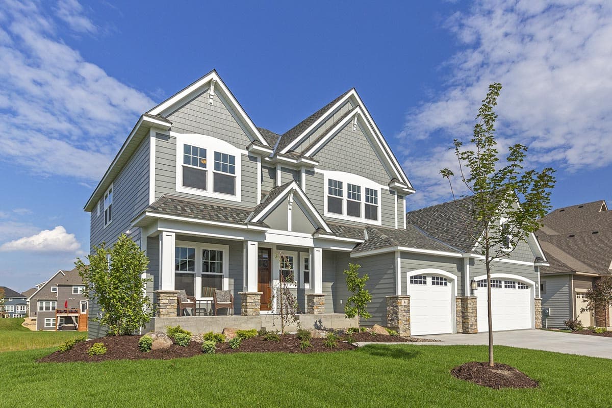 Two-story house plan exterior with gabled dormers, covered front porch, stone accents, and a three-car garage.