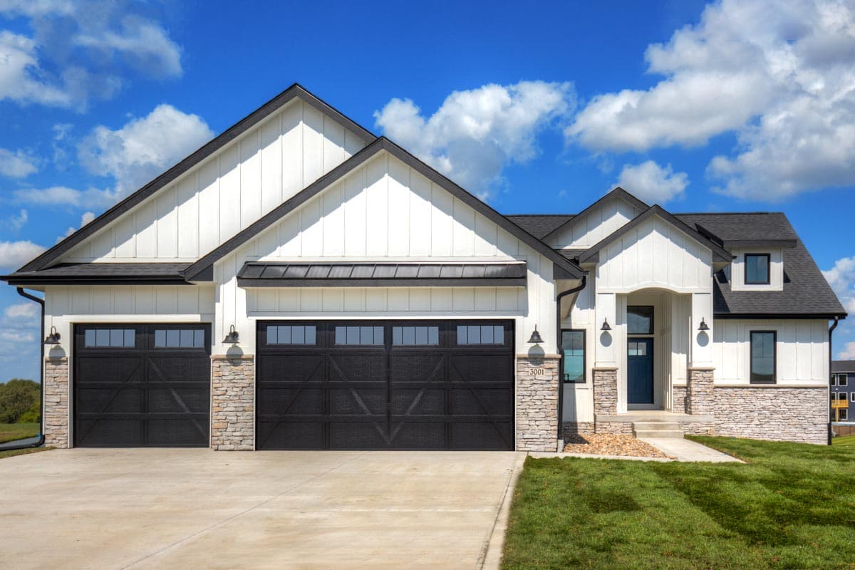 Modern Farmhouse house plan exterior with three-car garage, stone accents, prominent gables, and covered entryway.