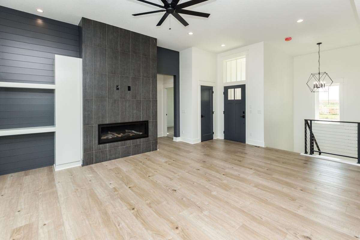 Living room with floor-to-ceiling tile fireplace, built-in shelving, and two dark gray doors with transom windows.