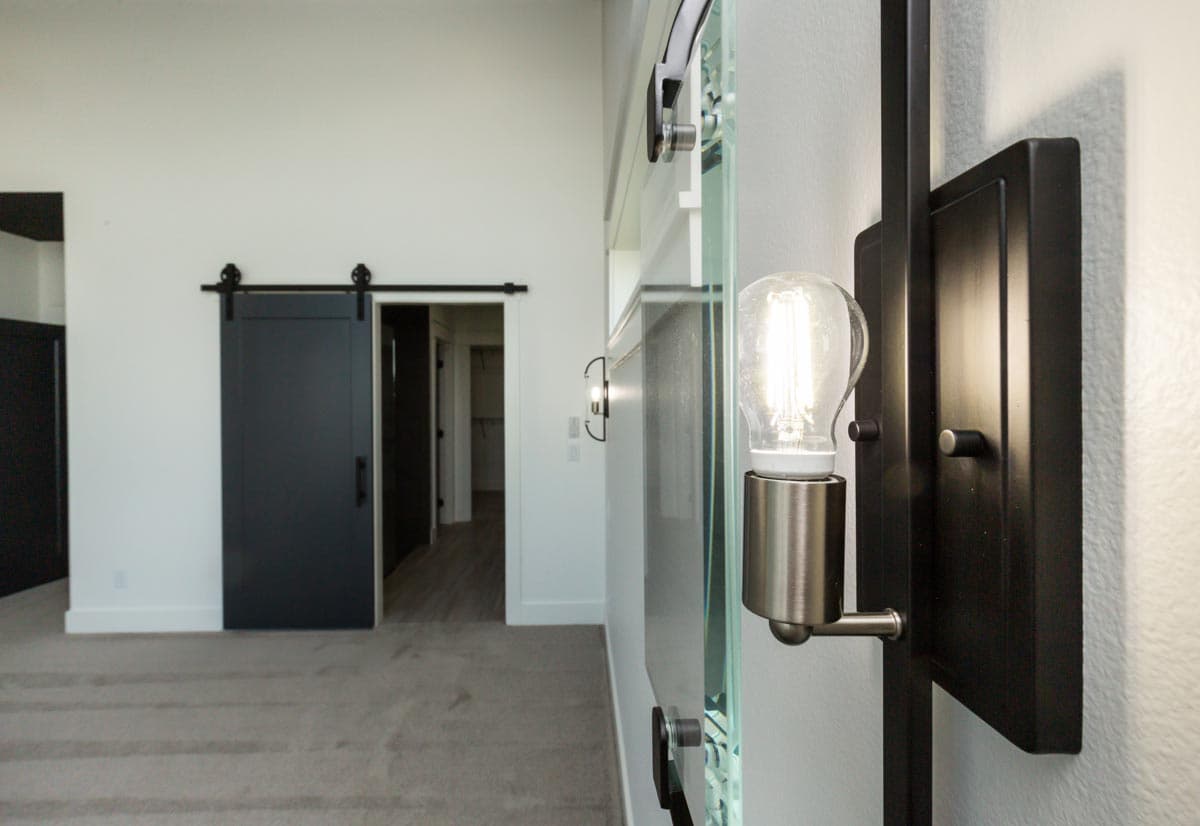 Interior view showing a black barn door and a wall sconce with exposed bulb.