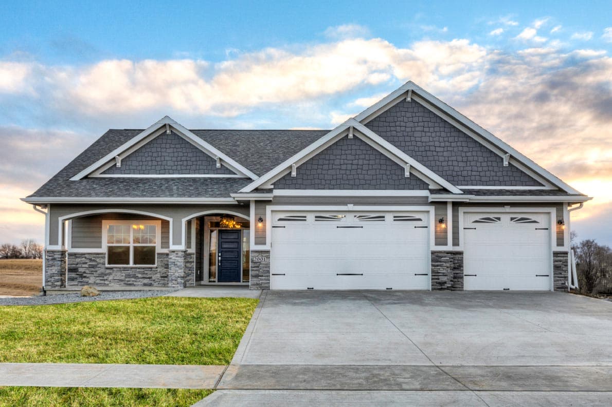 House plan exterior. Ranch style with two stories, gabled roof, stone accents, and a three-car garage.