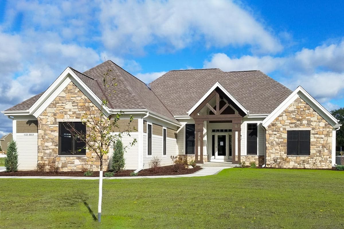 House plan exterior with stone accents, gable roof, and covered front entry. Features an exposed timber truss and multiple windows.
