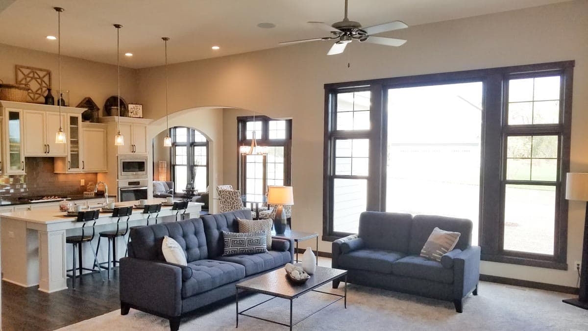 Open concept living area with kitchen island, sofas, and large windows.