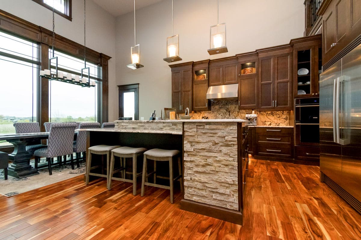 Contemporary kitchen with island, stone accents, dark wood cabinetry, stainless steel appliances, and large dining area windows.