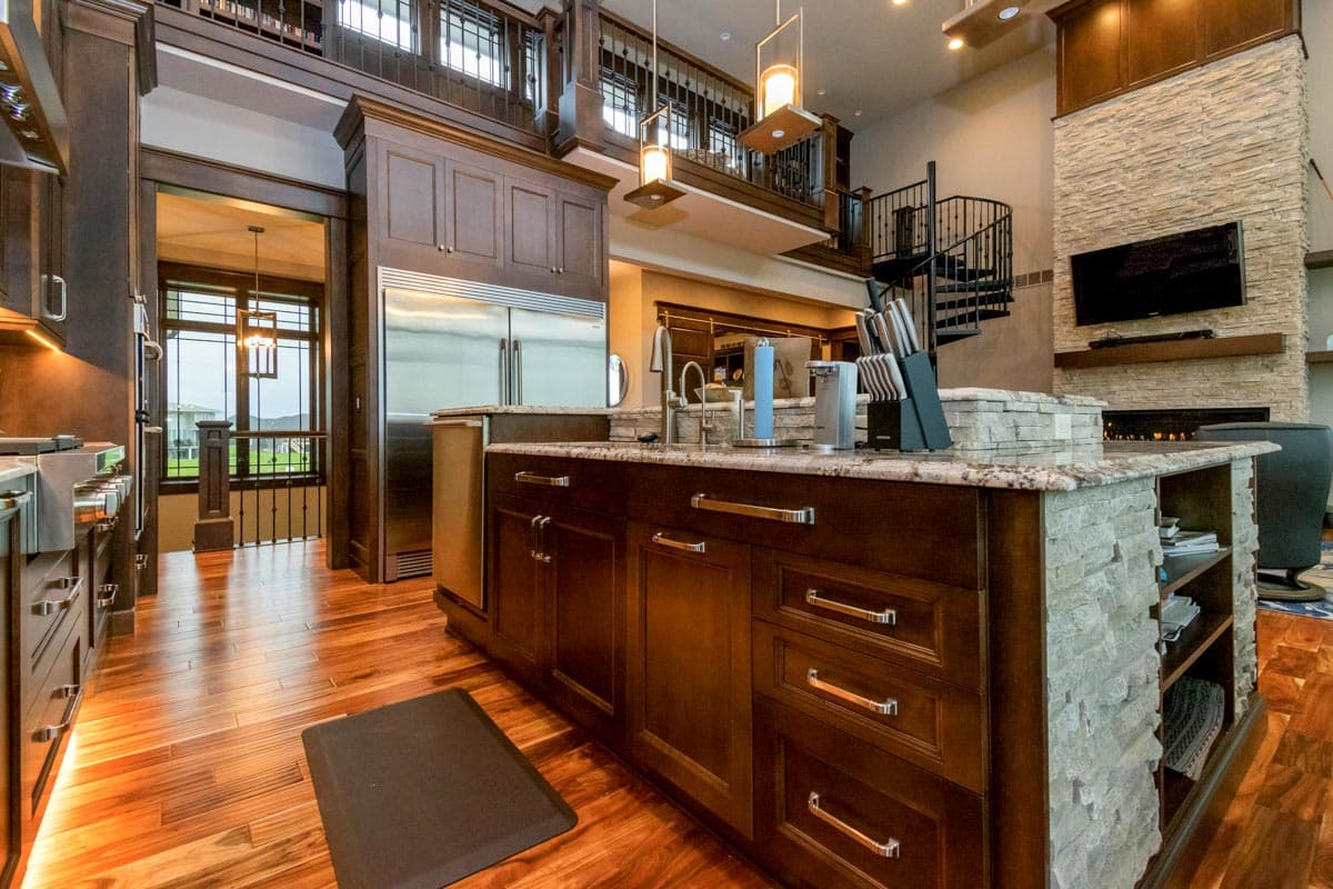 Kitchen with dark wood cabinetry, granite island, stainless steel appliances, and spiral staircase leading to upper level.