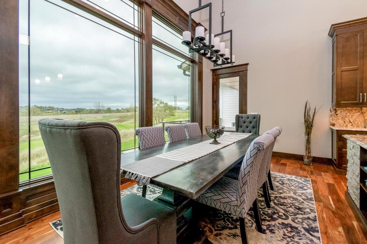 Dining room with large windows, dark wood table, upholstered chairs, and chandelier.