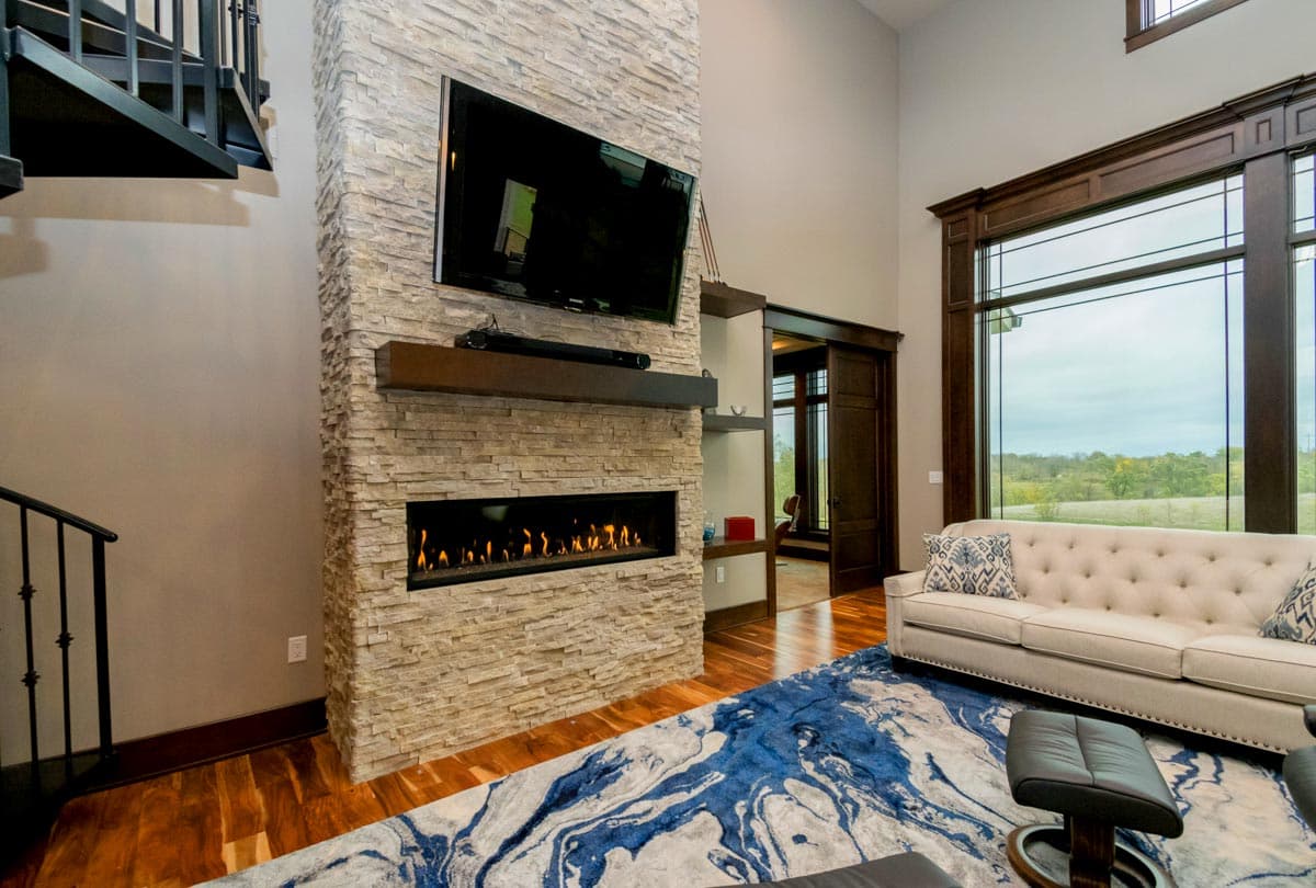 Living room with floor-to-ceiling stacked stone fireplace, modern linear fireplace, and large windows.