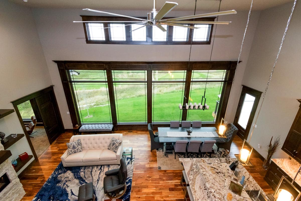 Great room with vaulted ceiling, fireplace, large windows, sectional sofa, dining table, and kitchen island.