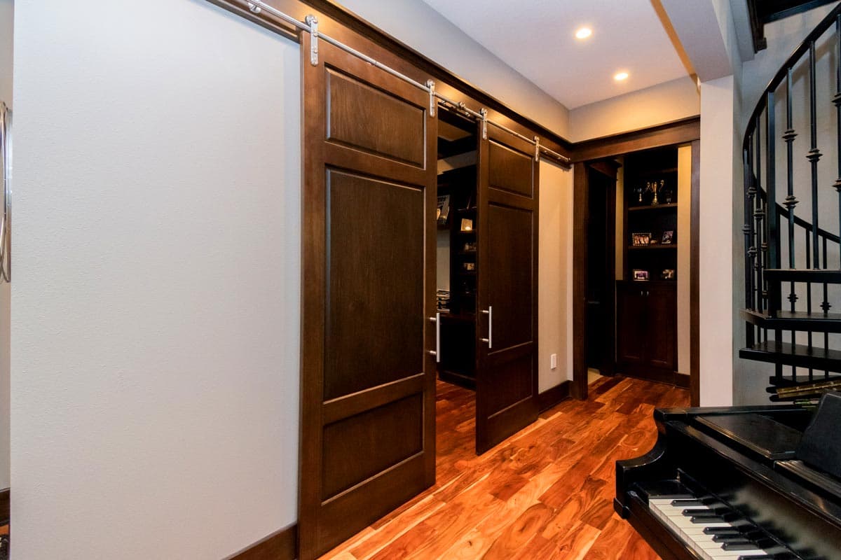 Interior view of a hallway with dark wood double barn doors, built-in shelving, and a spiral staircase.
