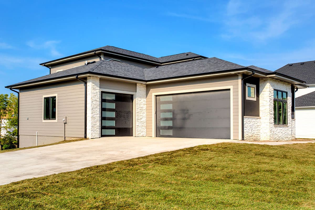Modern house plan exterior with two-car garage, stone accents, horizontal siding, and glass panel garage doors.