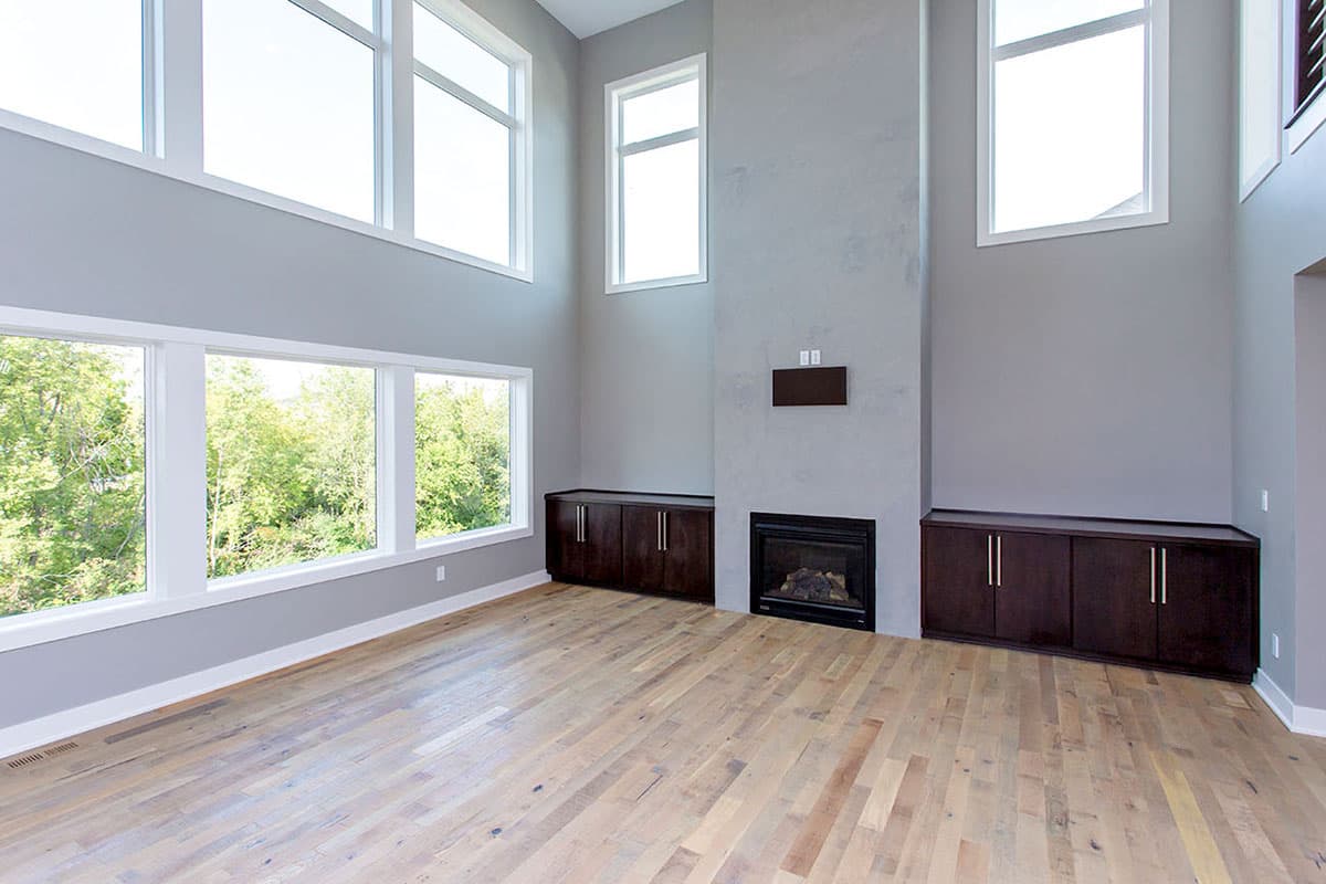Great room with two-story windows, fireplace, built-in cabinets, and hardwood floors.