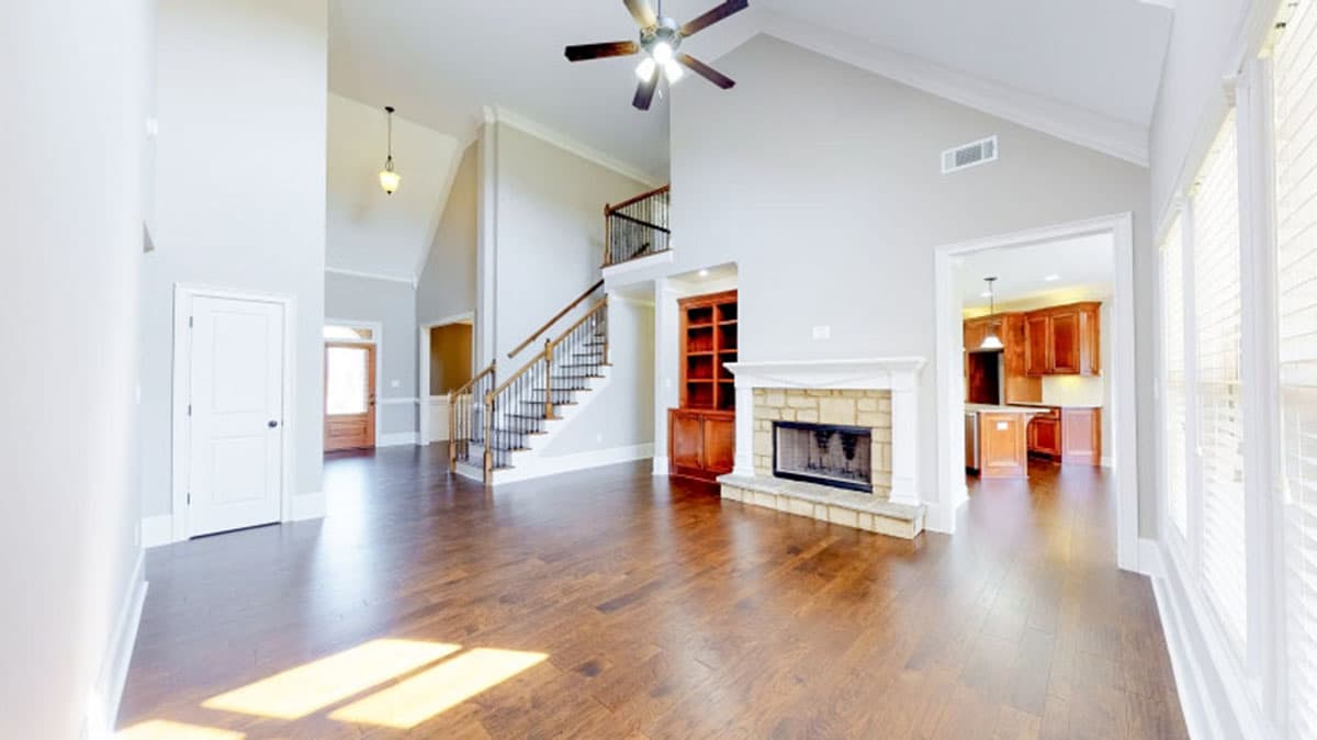 Great room interior featuring a stone fireplace, built-in bookshelves, vaulted ceiling, and open access to kitchen.