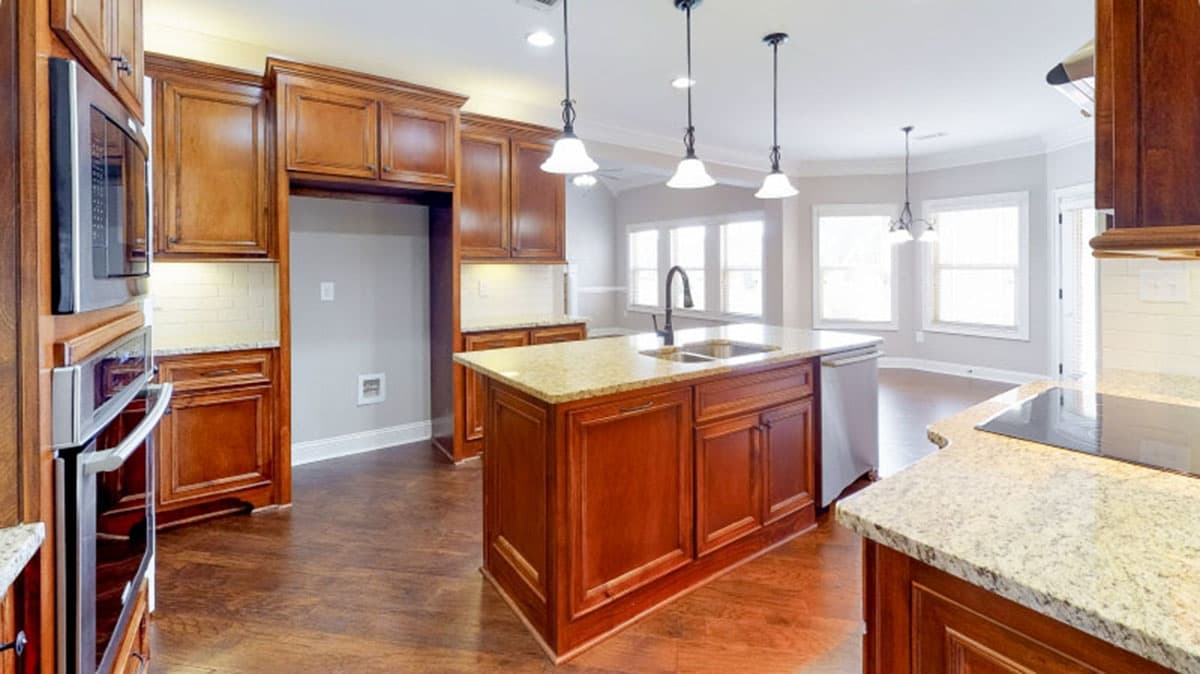 Kitchen with large island, granite countertops, stainless steel appliances, and pendant lighting overlooking dining area.