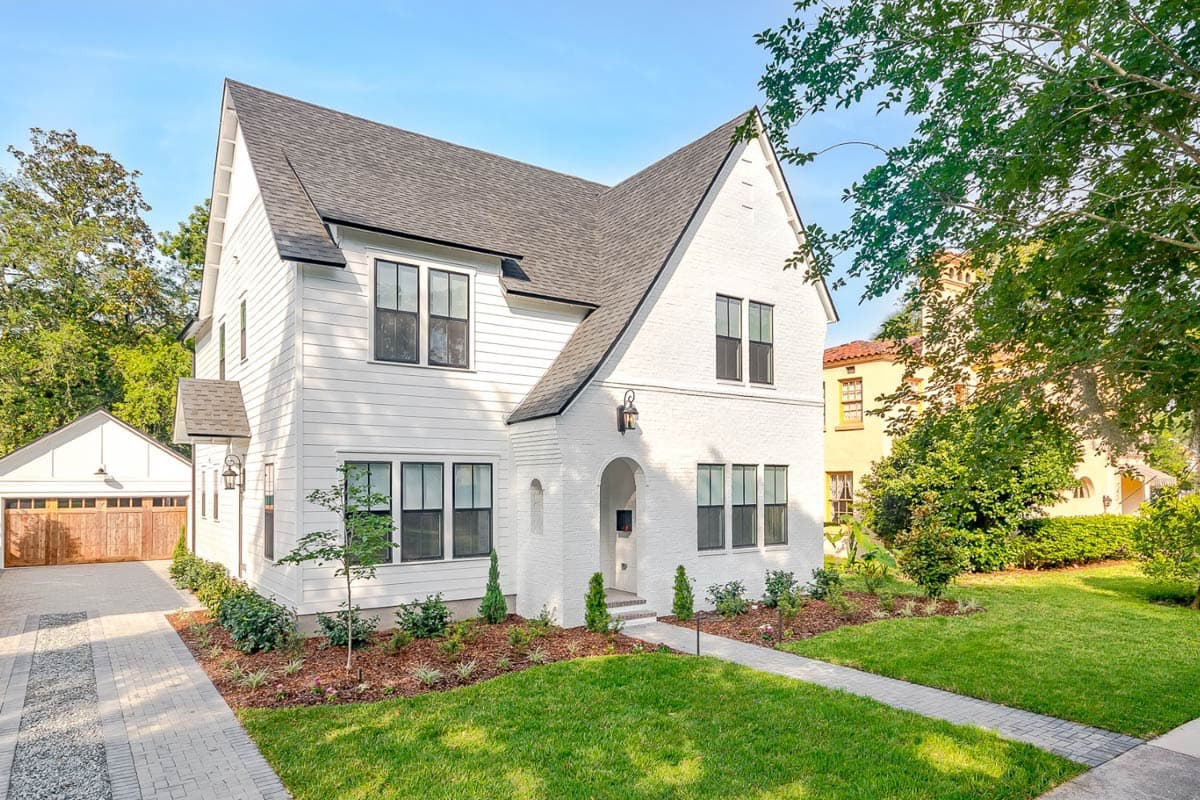 House plan exterior. Two-story Modern Farmhouse with gabled roof, brick archway, and attached garage. Includes a landscaped front yard.