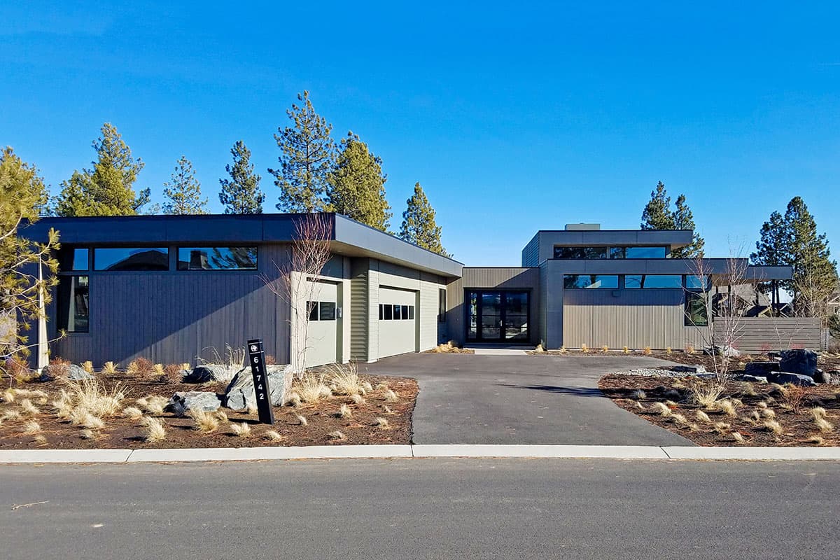 Modern house plan exterior with a low-pitched roof, horizontal siding, a two-car garage, and expansive windows.