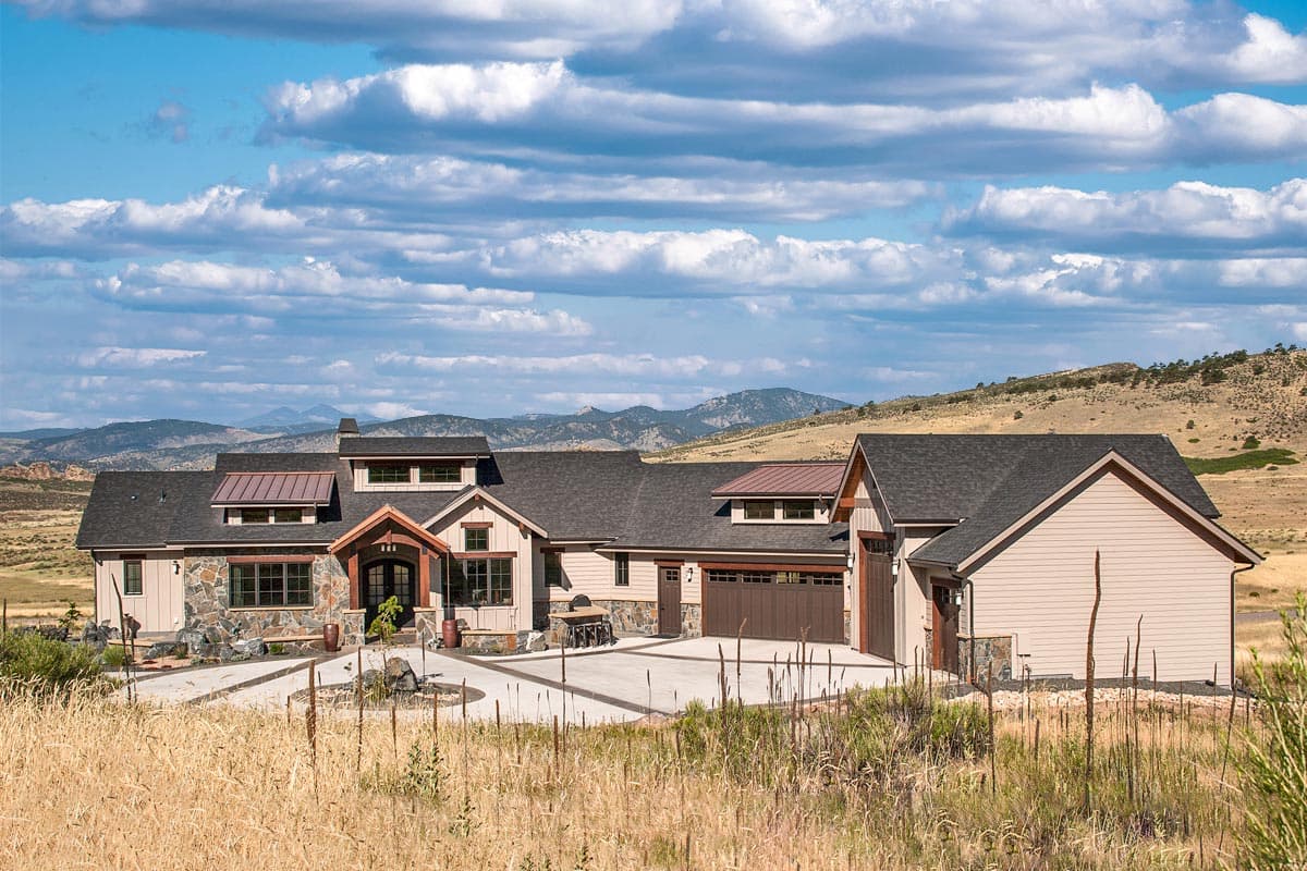House plan exterior. Ranch-style home with stone facade accents, multiple gables, and a prominent front entry porch. Attached garage.
