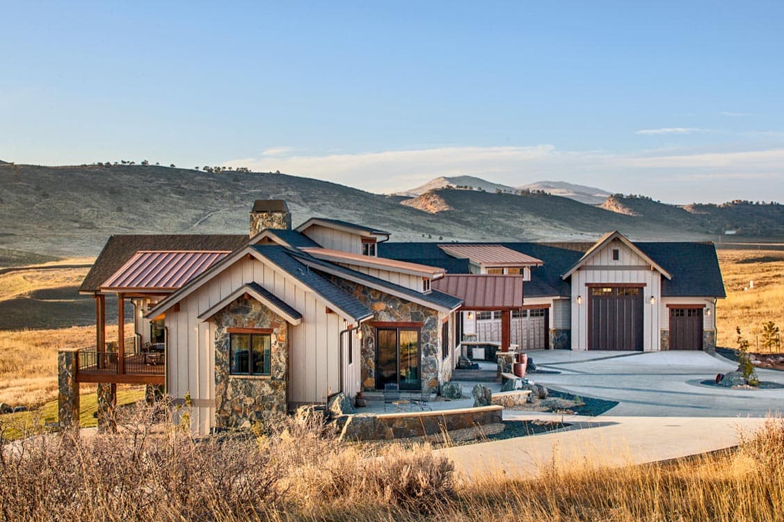 House plan exterior: modern ranch style, multi-level rooflines, stone accents, covered deck, and attached garage.