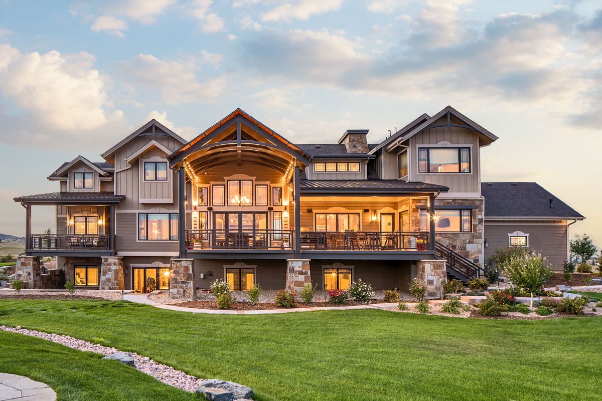 House plan exterior with multiple gables, covered decks, and stone accents. Two stories visible.