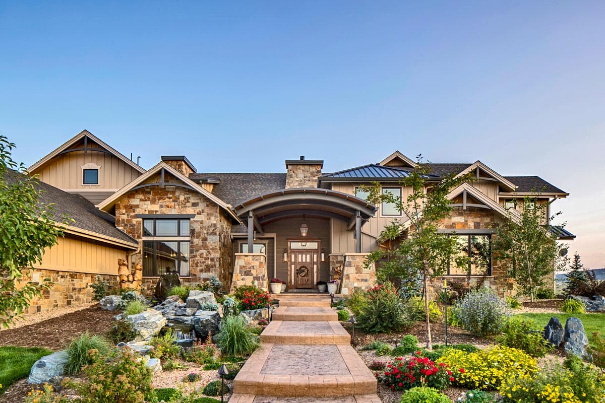 House plan exterior: two-story residence with stone accents, gables, arched entry, and prominent chimney.