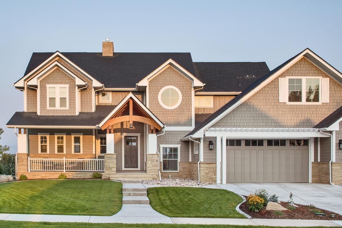 Craftsman style house plan exterior with covered porch, multiple gables, dormers, stone accents, and a two-car garage.