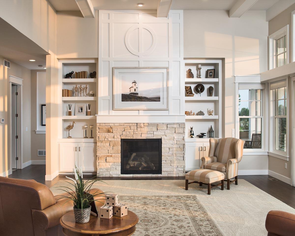Great room with stone fireplace, built-in shelving, coffered ceiling, and large windows.