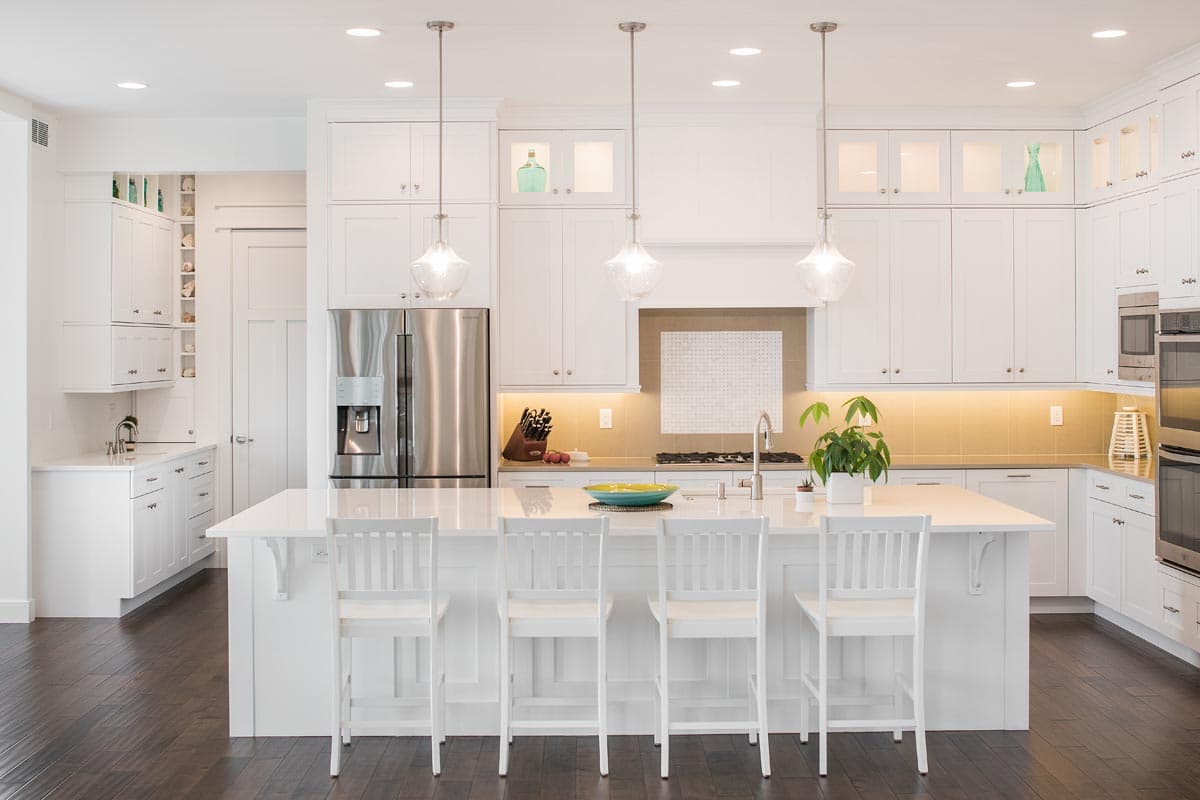 Modern kitchen featuring white cabinetry, stainless steel appliances, a large island with seating, and pendant lighting.