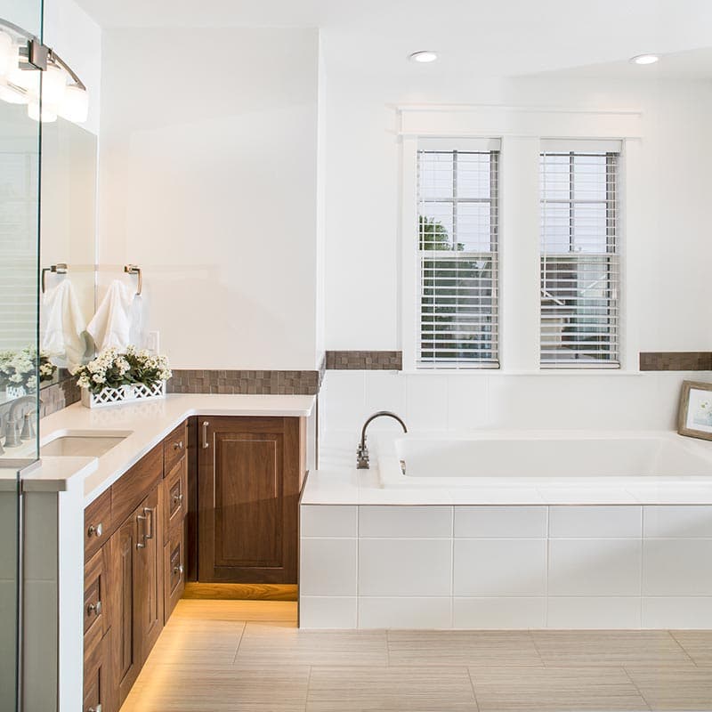 Bathroom with wood vanity, dual sinks, soaking tub, and large tiled shower.