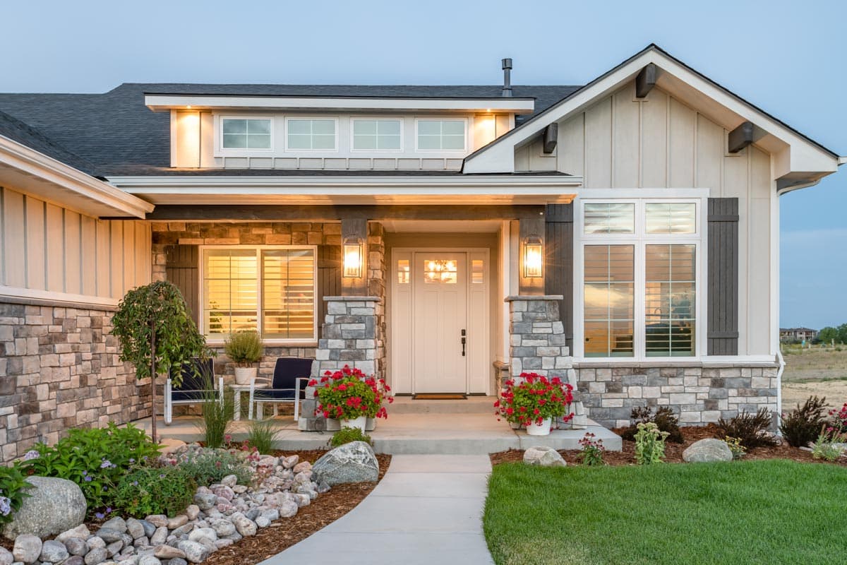 Modern Farmhouse house plan exterior with stone accents, covered entry with glass door, and gable rooflines with exposed rafter tails.