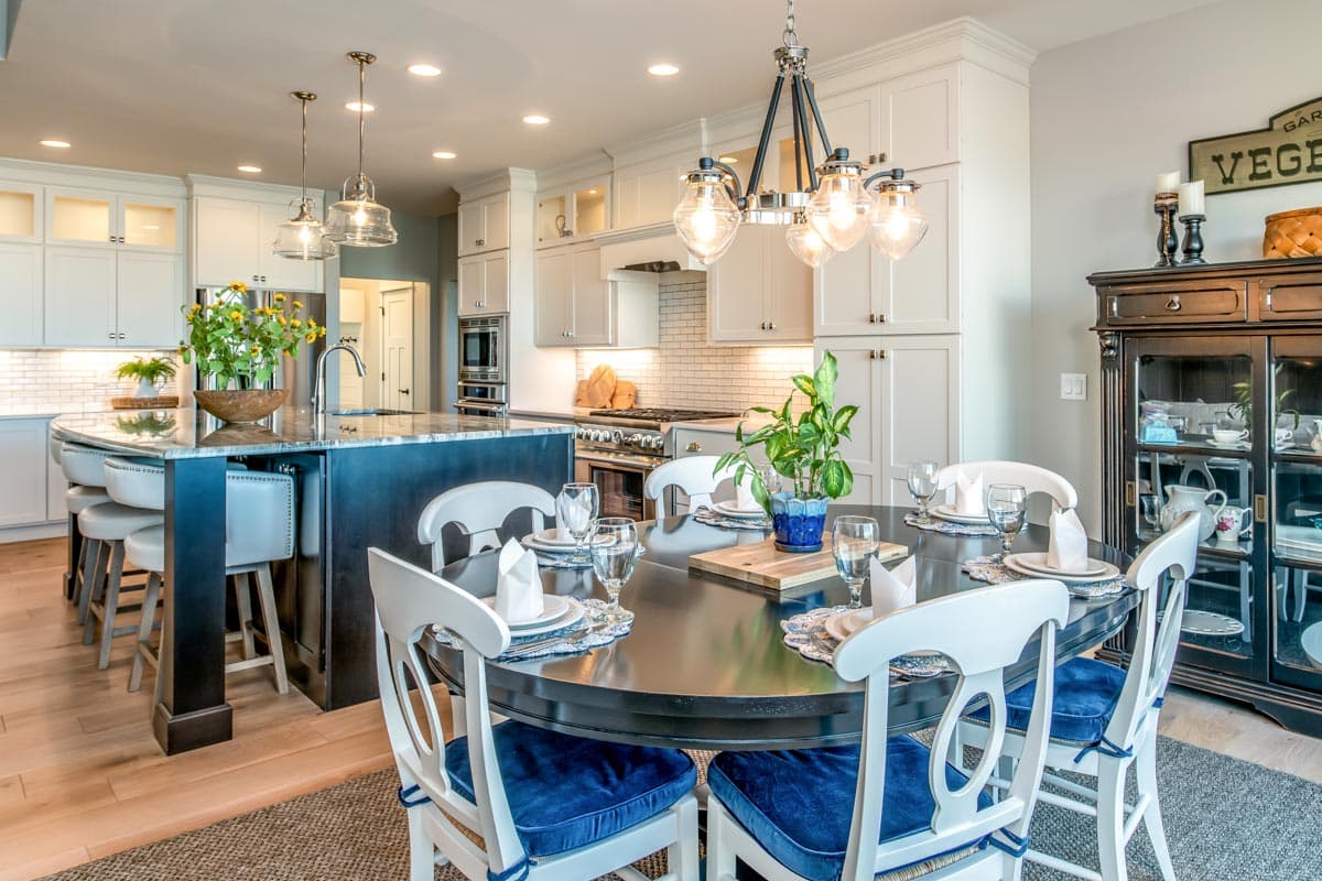 Kitchen and dining area with large island, white cabinetry, stainless steel appliances, and round dining table.