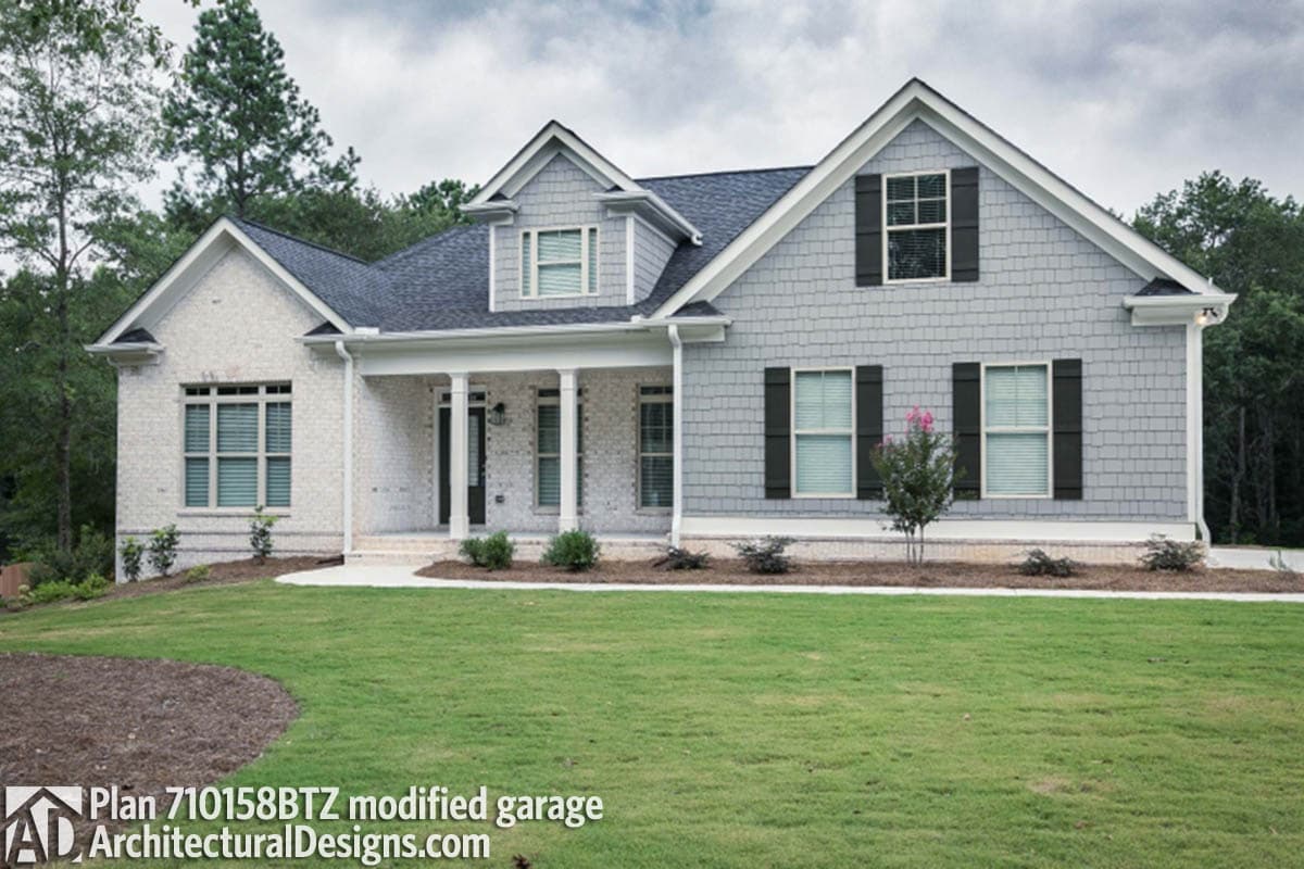 House plan exterior: Two-story home with brick and shingle siding, covered front porch, and prominent gables.
