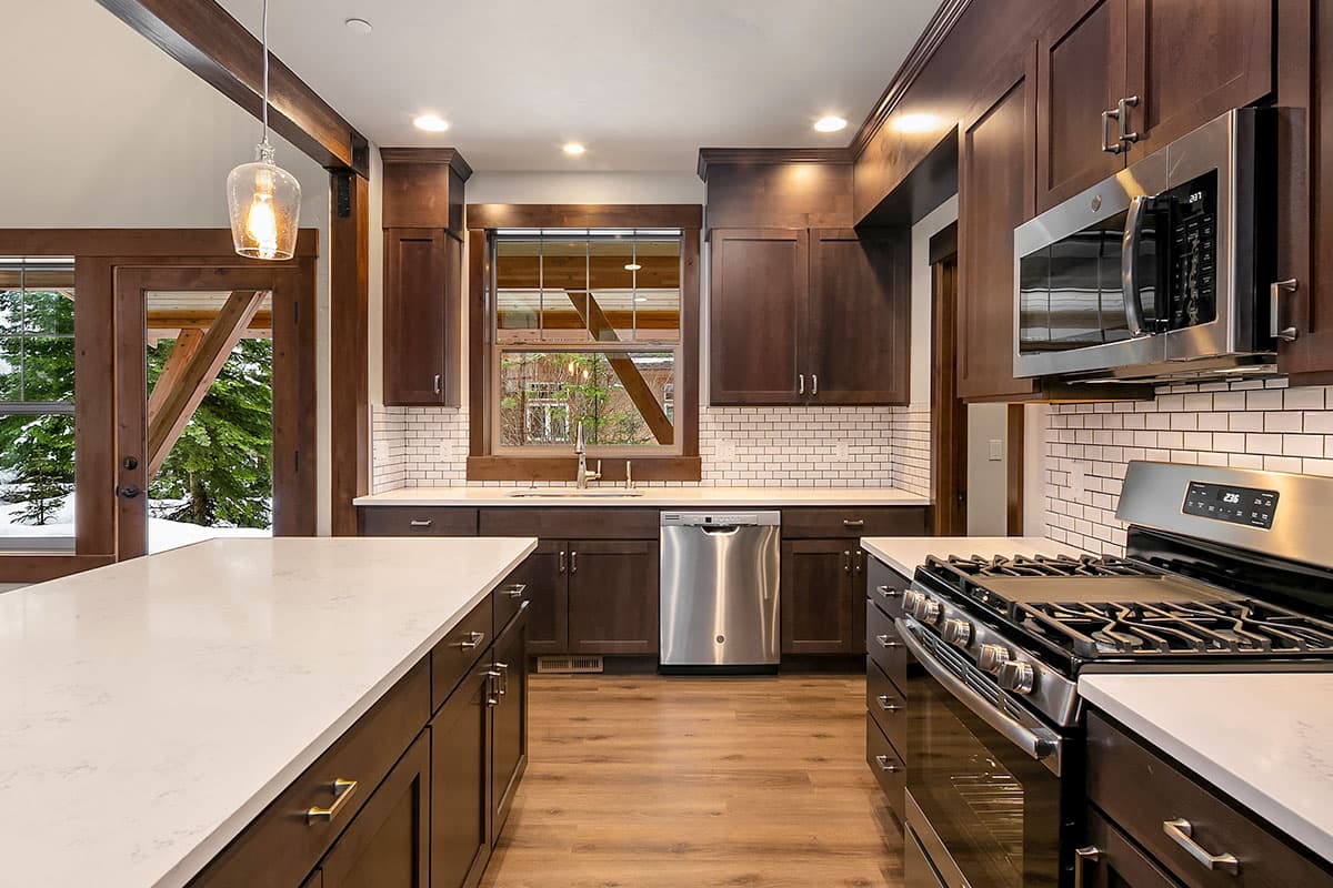 Kitchen with dark wood cabinetry, white subway tile backsplash, stainless steel appliances, and a large island with a white countertop.