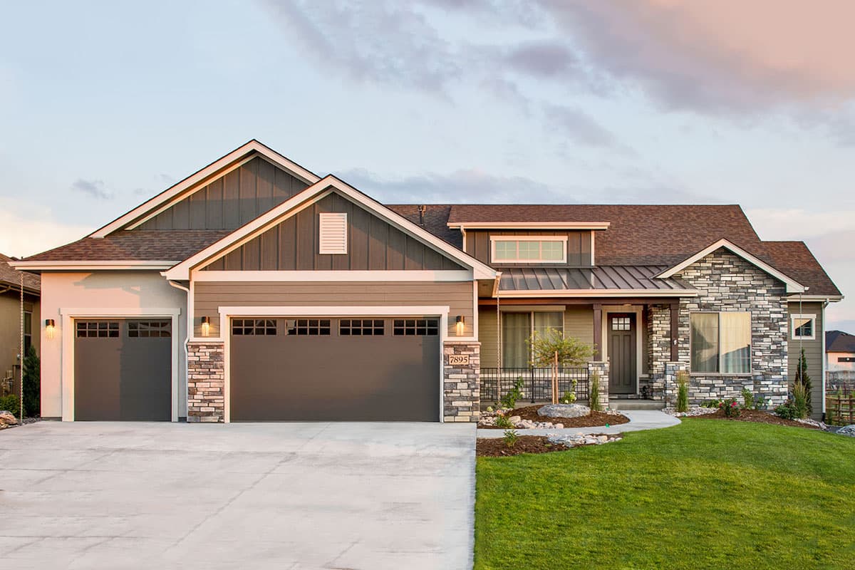 House plan exterior. A single-story Craftsman home with a stone and wood facade, a covered porch, and a garage with two bays.