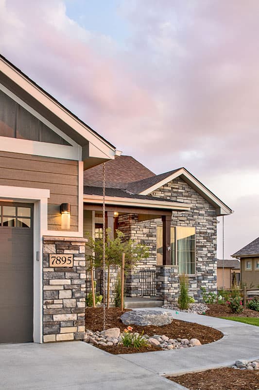 Modern Farmhouse style house plan exterior with stone accents, covered porch with wood columns, gabled rooflines, and attached garage.