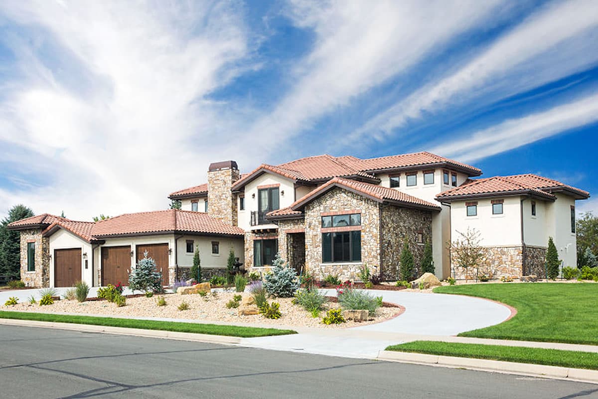 House plan exterior featuring stucco, stone accents, and a tile roof. Includes a detached garage, chimney, and multi-gabled rooflines.