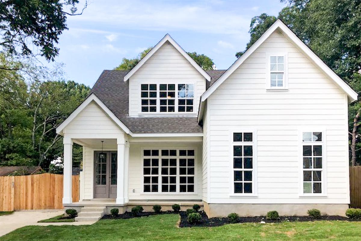 House plan exterior. Two-story Modern Farmhouse with gabled roof, front porch, and dormer. Features include multi-paned windows and horizontal siding.