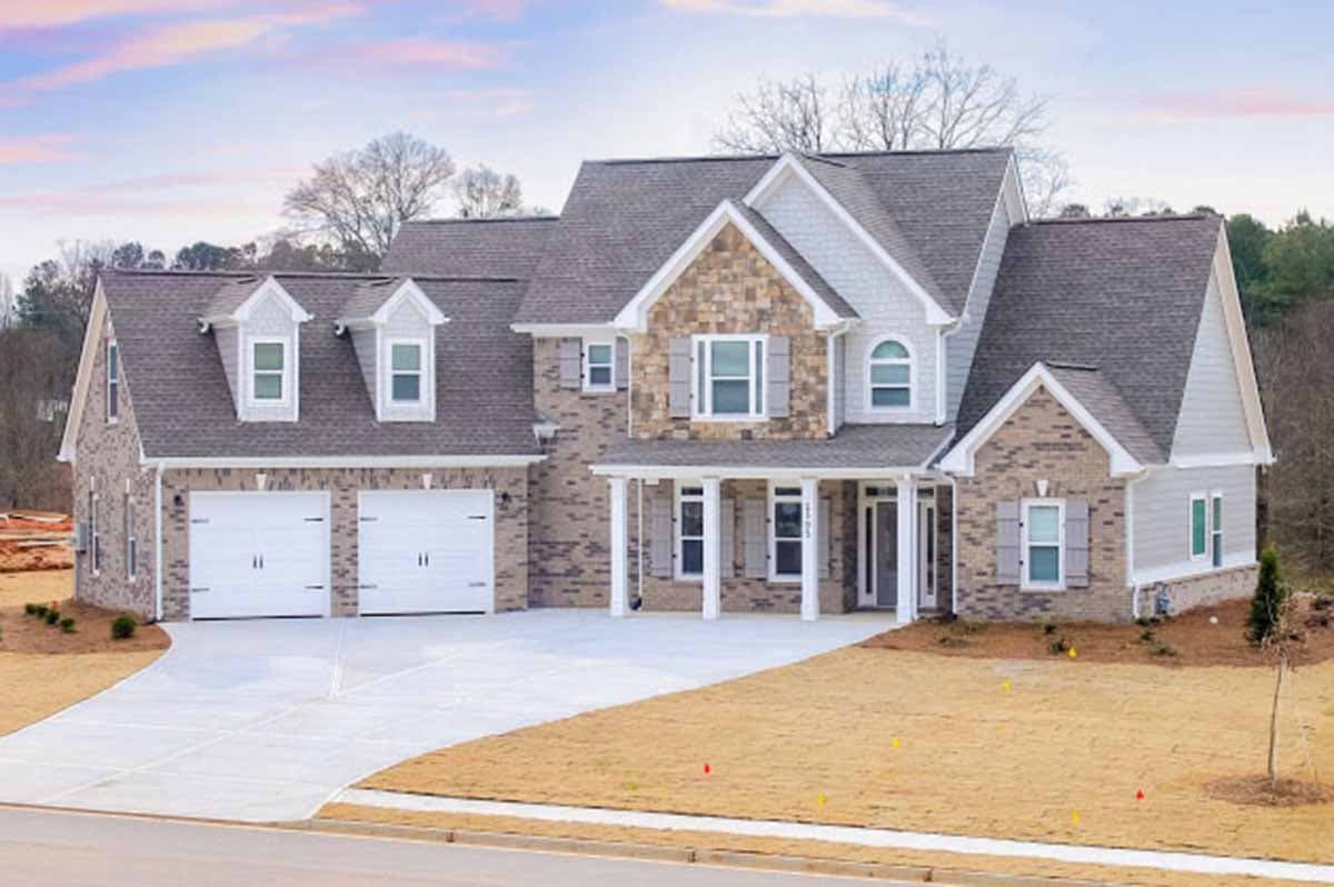 House plan exterior. Two-story with brick, stone, and siding. Features include multiple gables, a front porch, dormers, and an attached garage.