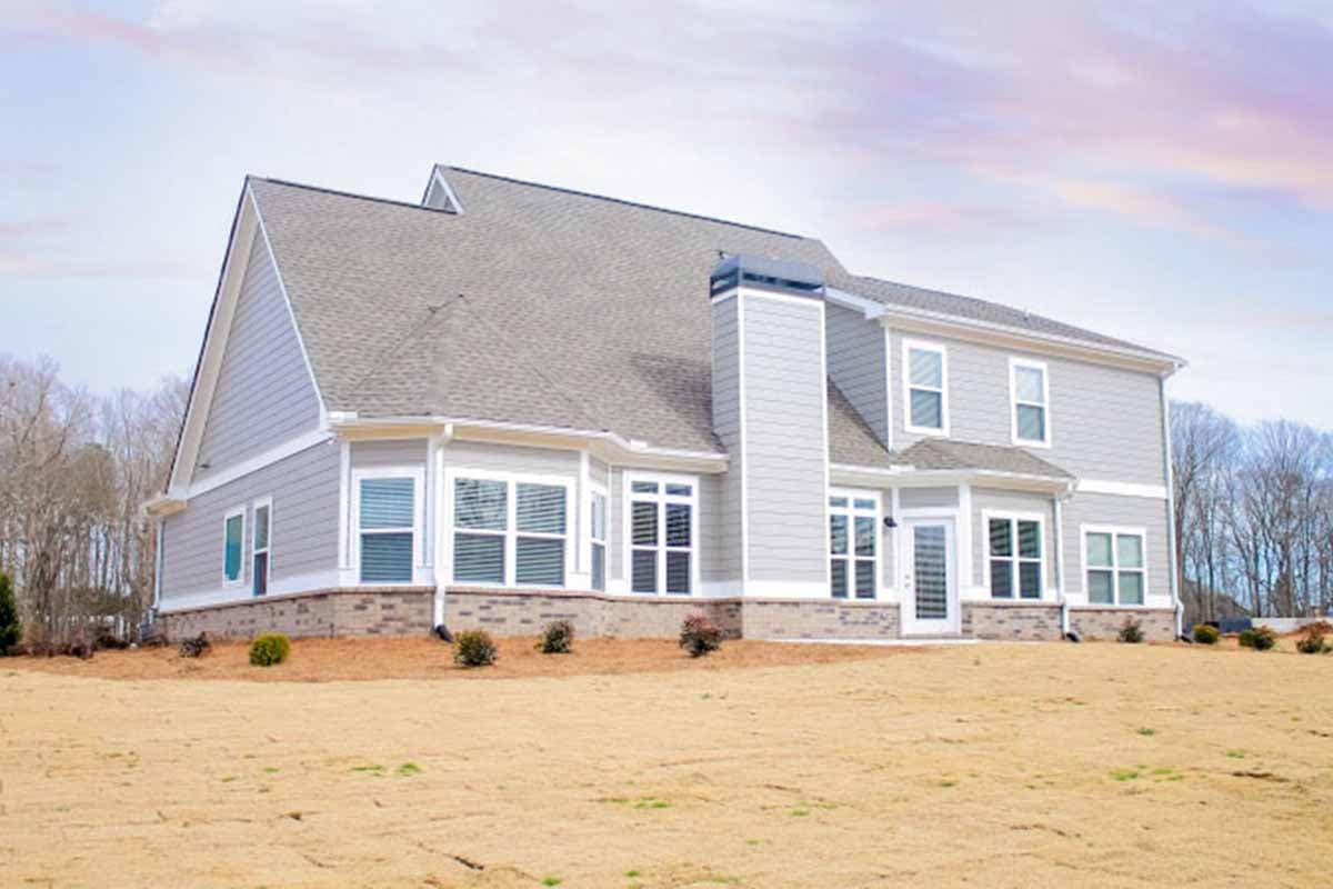 House plan exterior with gabled rooflines, large bay windows on the first floor, and a prominent chimney.