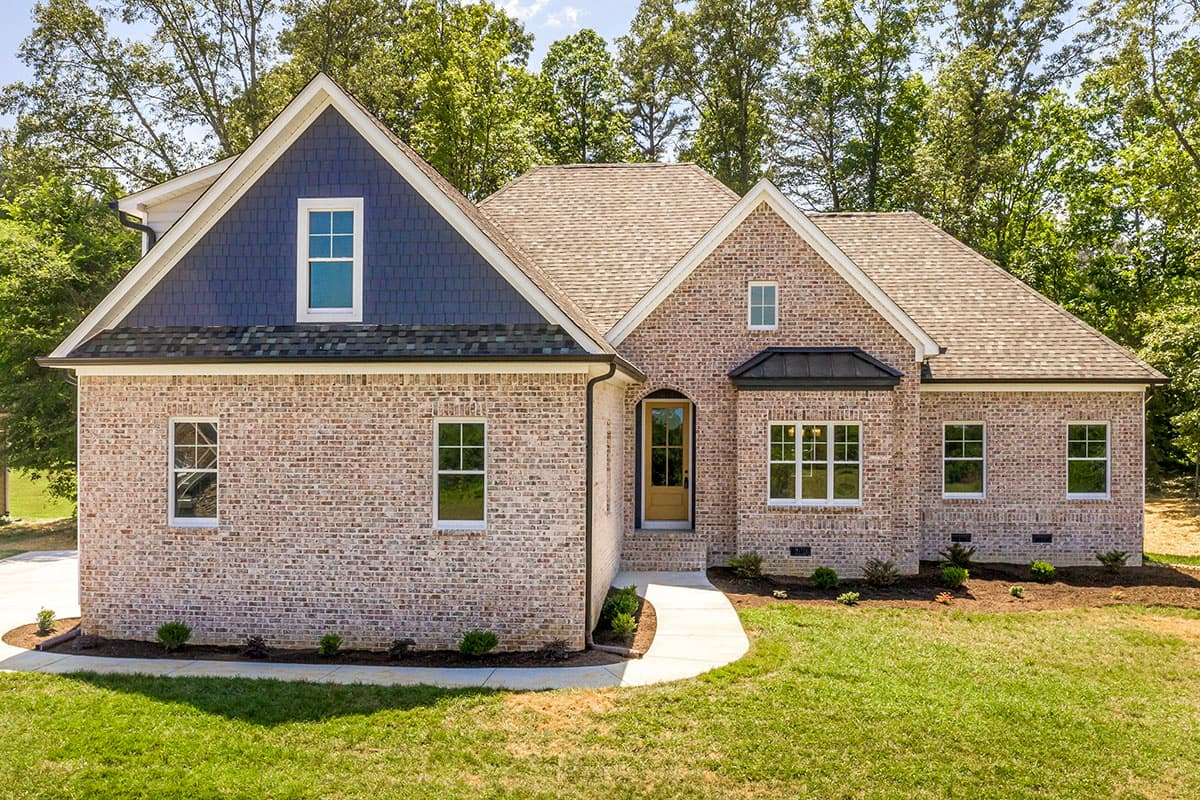 House plan exterior with brick facade, prominent gable with blue shingle siding, and arched entryway.