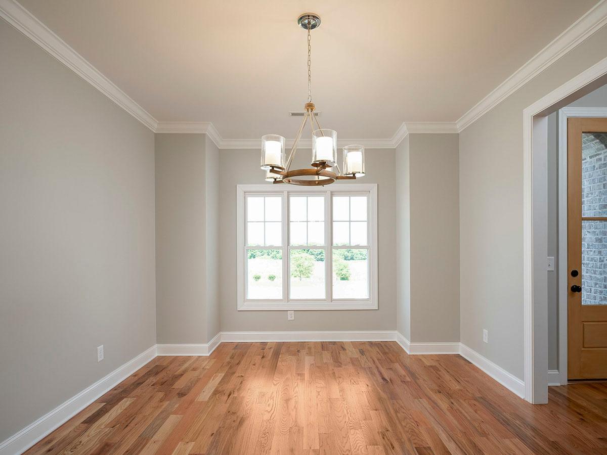 Interior view of a room with hardwood floors, crown molding, a chandelier, and a large window.