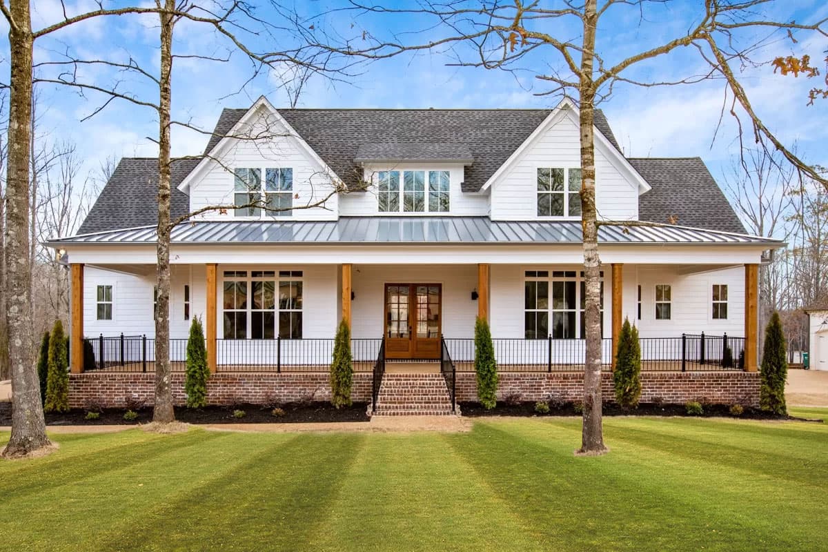 House plan exterior: Modern Farmhouse style, two stories, wide covered porch with wood columns, multiple gables, and metal roof.