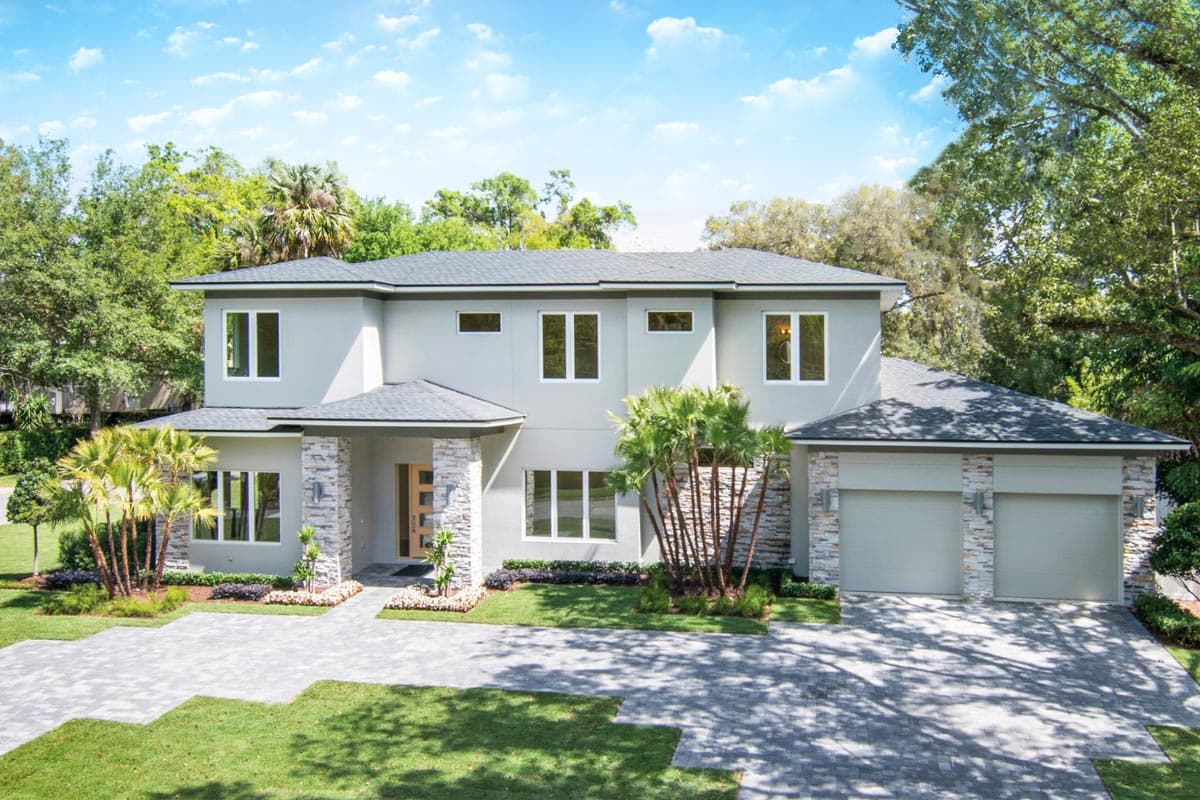 House plan exterior with two stories, flat roof, stone accents, and a covered entry. Features a two-car garage with matching stone detailing.