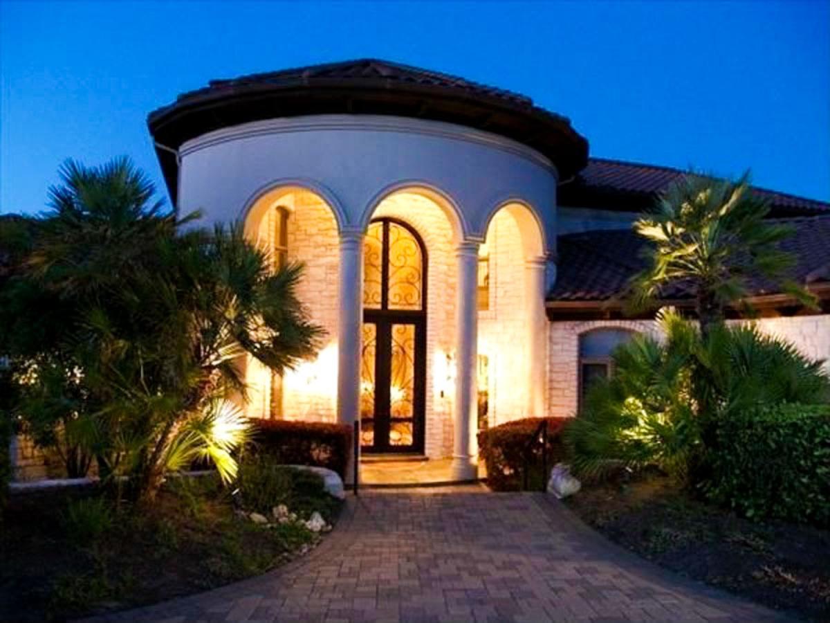 House plan exterior with curved facade, arched entryway, tiled roof, and stone accents.