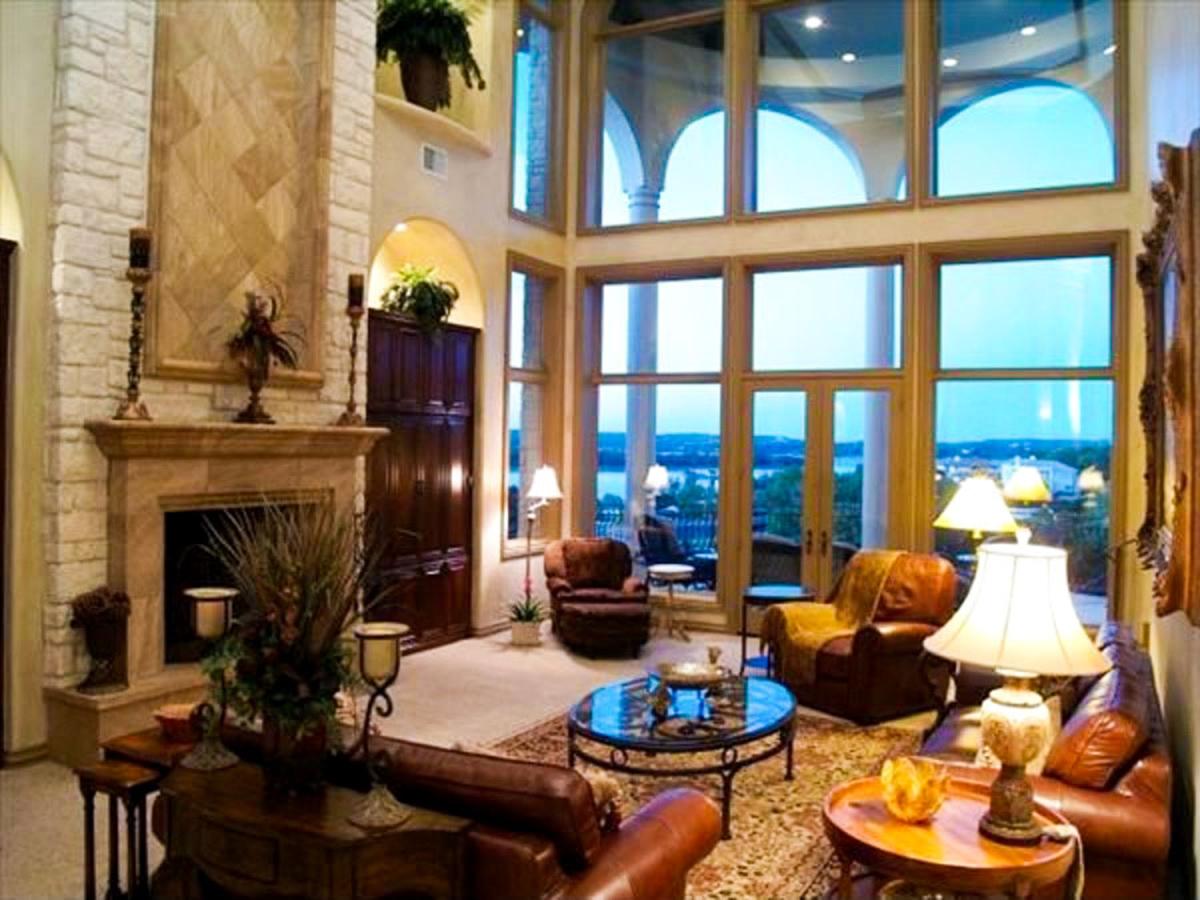 Living room with stone fireplace, vaulted ceiling, and large windows offering a scenic view.