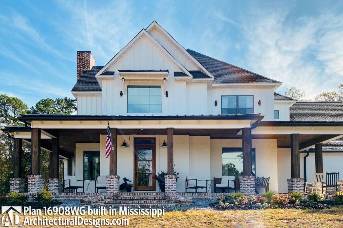 Modern Farmhouse house plan exterior with a wide covered porch, board and batten siding, brick accents, and multiple gables.