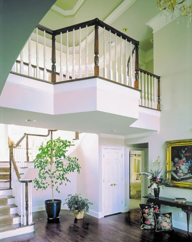 Interior view of a two-story foyer with a staircase, upper-level landing, and decorative balusters.