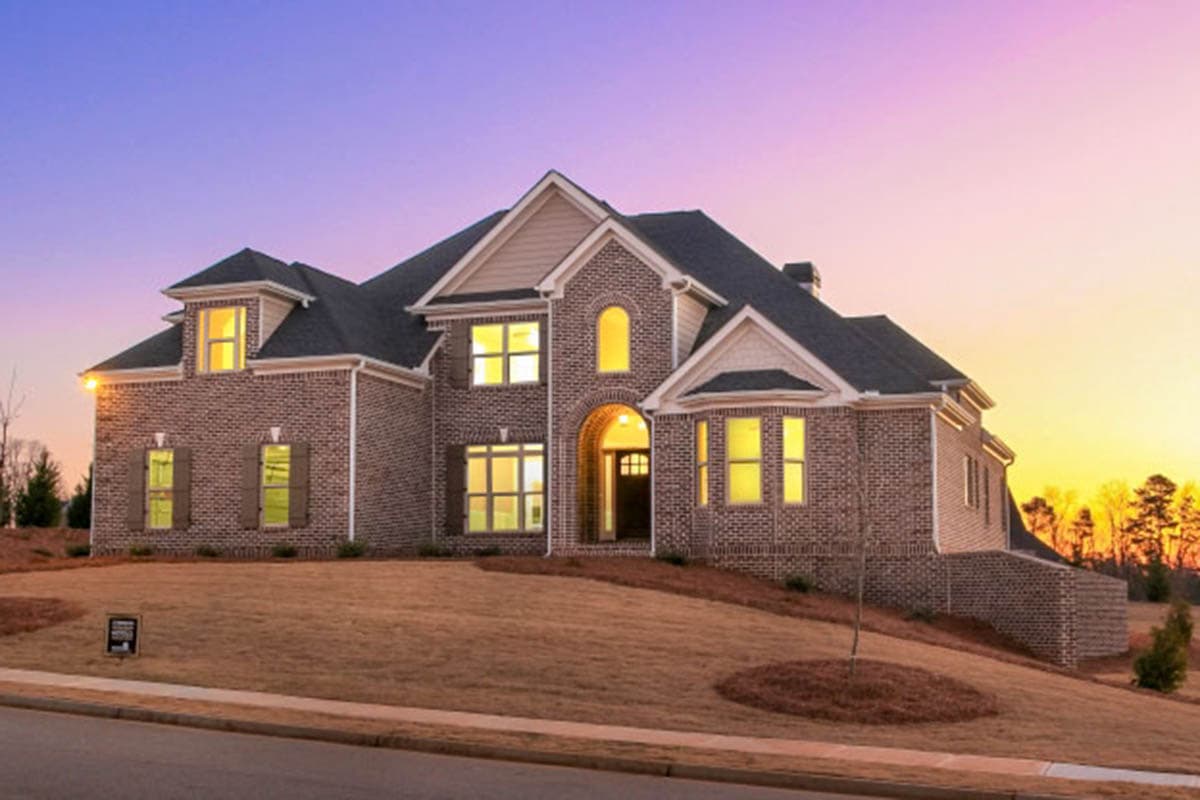 House plan exterior with brick facade, arched entry, dormers, and multiple gables. Two stories visible.
