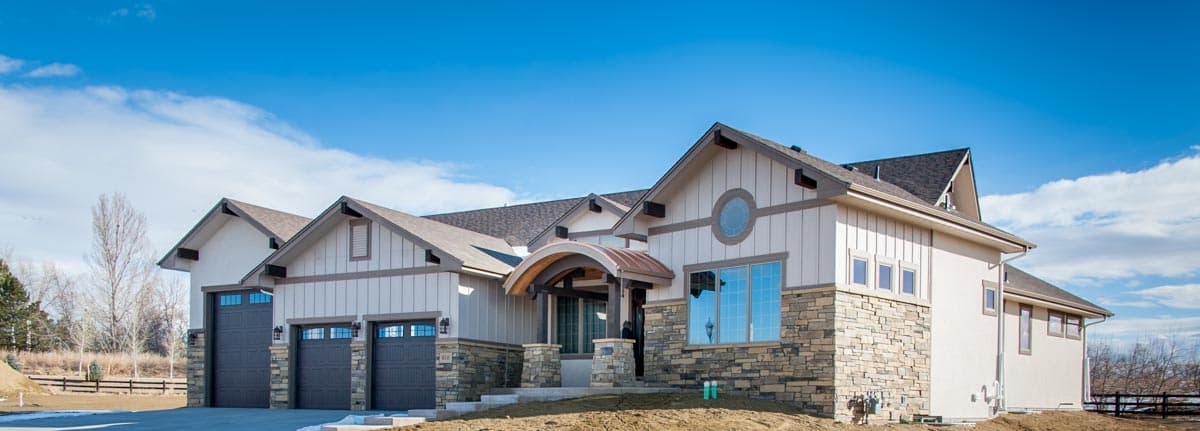 House plan exterior: Contemporary style with stucco and stone facade, multiple gables, arched entry, and a four-car garage.