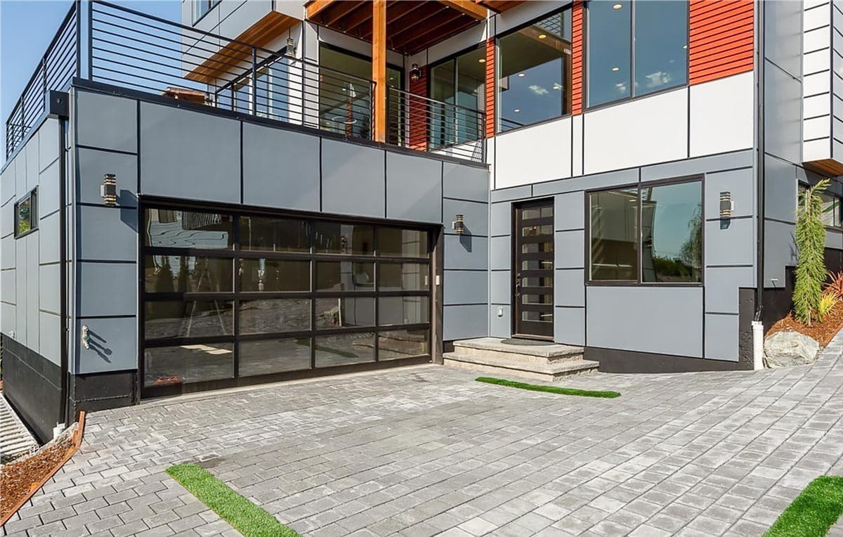 Modern house exterior with glass garage door, multiple levels, balconies, and a contemporary entry.