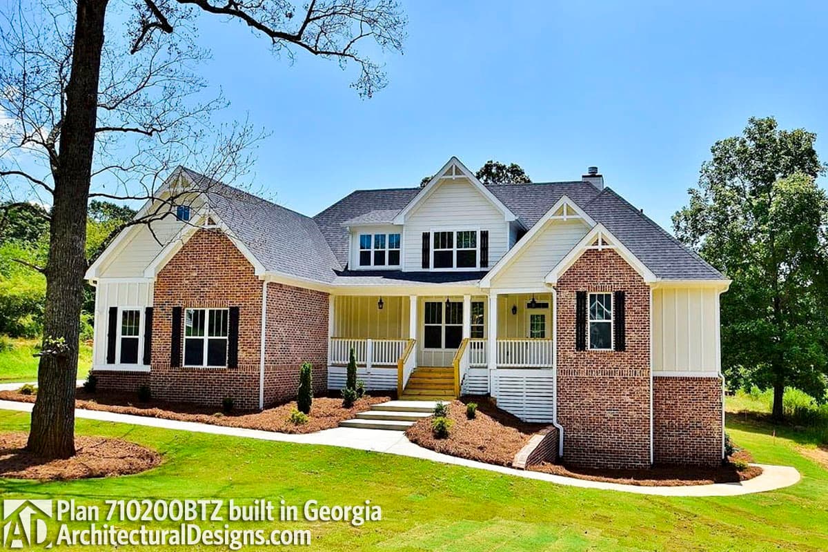 House plan exterior: Two-story Modern Farmhouse with brick facade, prominent gables, dormers, and wraparound porch.